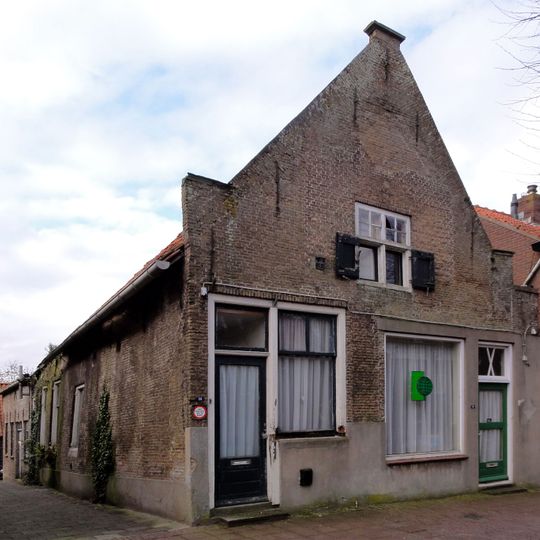 Pand met IJsselstenen puntgevel, voorzien van vlechtingen en geprofileerde dekplaten opzij en op de top