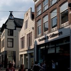 Pand met verminkte gepleisterde klokgevel met gevelsteen en gewijzigde ramen in pui