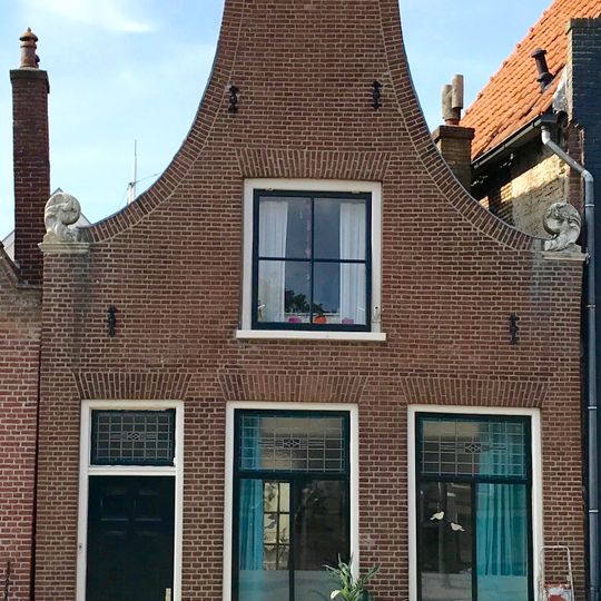 Pand met smalle klokgevel met aanzetkrullen en driehoekig fronton in top