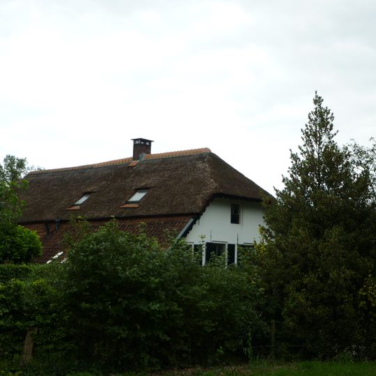Eenvoudige veluwse boerderij, onder een hoog met riet en pannen gedekt wolfdak en met gepleisterde gevels