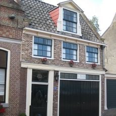 Huis met dwars zadeldak. Oorspronkelijk deur en bovenramen