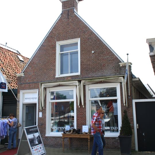 Eenvoudige woning met geprofileerde kozijnen en aanzetlijsten onder zadeldak tegen topgevel