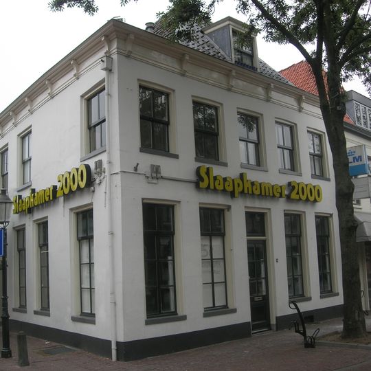 Witgepleisterd hoekpand met verdieping gedeeltelijk onder schilddak, met dakkapel