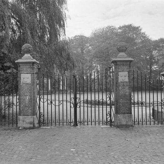 Vier gemetselde hekpalen met hardstenen ornamenten en smeedijzeren hek