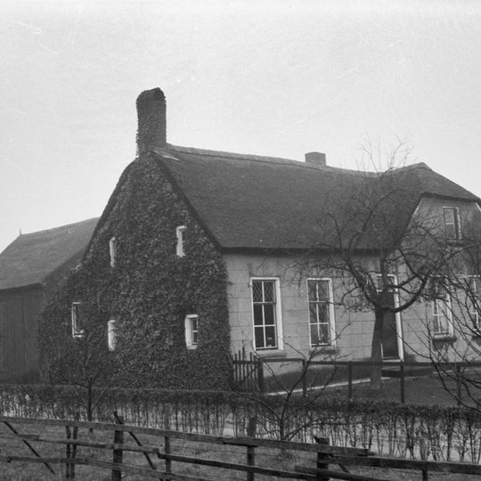 Boerderij met rechts afgeknotte puntgevel en links uitbouw onder zadeldak evenwijdig aan de straat