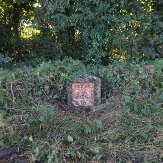 Milestone, just E of entrance to Claydon Fields.