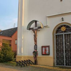 Dřevěný kříž v Třeštině u zdi kostela