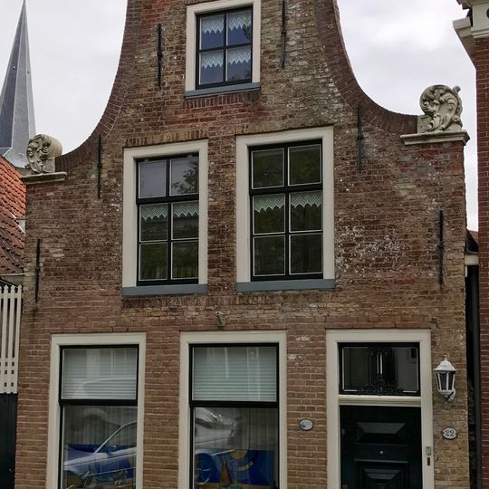 Pand onder zadeldak tegen klokgevel met gebeeldhouwde aanzetkrullen en kroonlijst