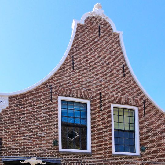 Pand onder zadeldak tegen gebeeldhouwde klokgevel