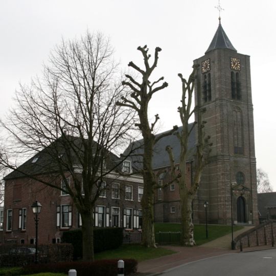 Noordelijk van de kerk gelegen herenhuis met verdieping en omlopend schilddak. Twee dakkapellen met eenvoudige gesneden zijstukken. Schilderachtige ligging achter twee oude platanen
