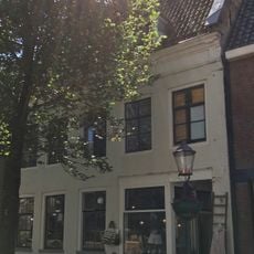 Vijf traveeën breed pand tussen topgevels met rechte kroonlijst met trigliefen onder dwars zadeldak met twee dakkapellen