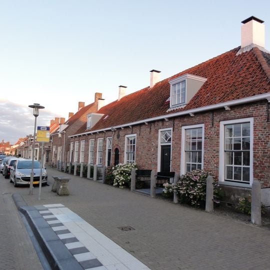 Complex dorpshuizen onder een kap, nok evenwijdig aan de straat. Schuifvensters. Tussen nr 94 en 96 een boogpoortje, hierboven een sierankers