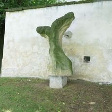 Kamenná plastika Ukřižovaný u zdi areálu kostela v Podlesicích