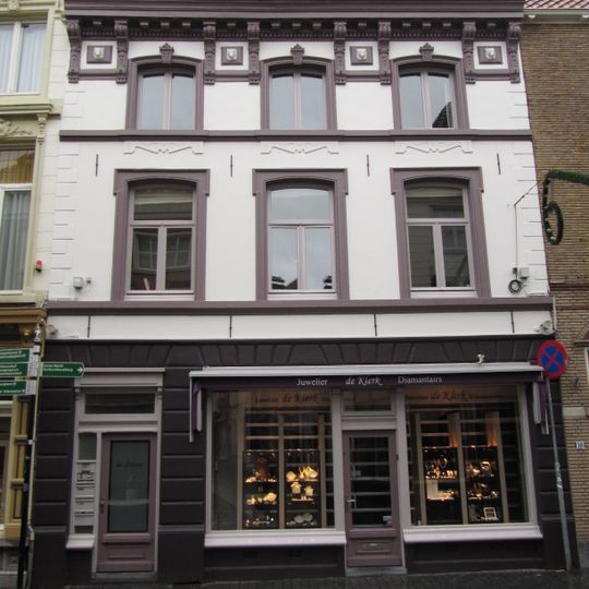 Huis met witgepleisterde en van stucversiering voorziene lijstgevel en hoog met rode pannen belegd zadeldak