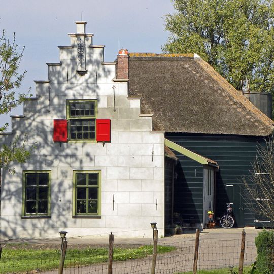 Grotendeels houten boerderij, waarvan het woongedeelte is voorzien van een trapgevel, met sierankers. Bedrijfsgedeelte nog met rieten dak