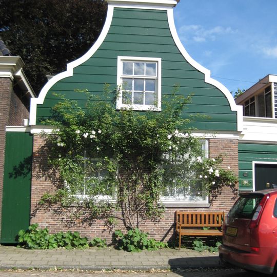 Houten dijkhuis met klokgevel , bakstenen onderpui