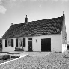 Huis onder zadeldak tussen zijtopgevels, 9-ruitsvensters aan de voorzijde. Gedeeltelijk wit geverfd