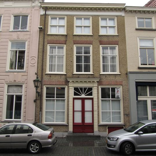 Huis met witgepleisterde lijstgevel en kroonlijst op voluutvormige consoles