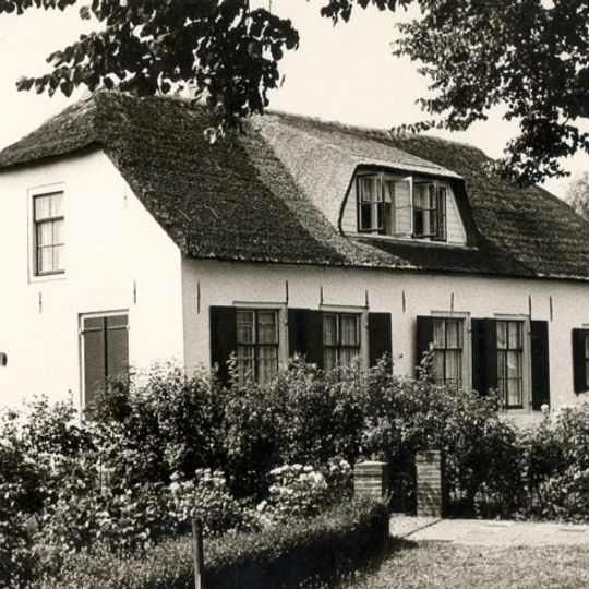 Boerderij bestaande uit een gepleisterd dwarshuis en een bedrijfsgedeelte, onder een met riet gedekt wolfdak