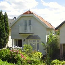 Houten huis met gerabatte wanden met zolderverdieping onder zadeldak met wolfeind