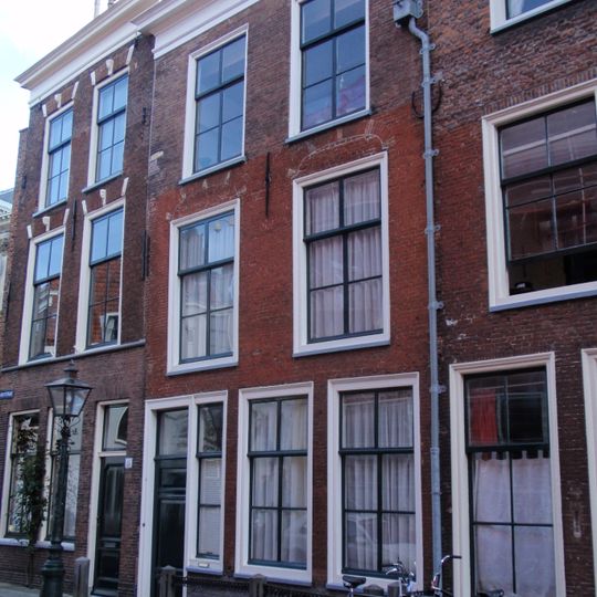 Pand met gevel met rechte kroonlijst met bogen boven de vensters. Empire-ramen