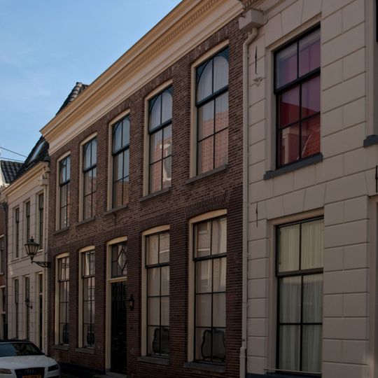 Pand met brede gevel met rechte kroonlijst, en halfrond beëindigde ramen op de verdieping
