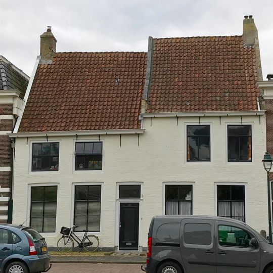 Pand bestaand uit twee gedeelten door in hoogte verschillend zadeldak tussen topgevels gedekt