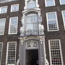 PAND met Lodewijk XIV lijstgevel, vijf vensterassen breed, met rijk versierde middenrisaliet, waarin gesneden omlijstingen (ranken, klauwstukken.