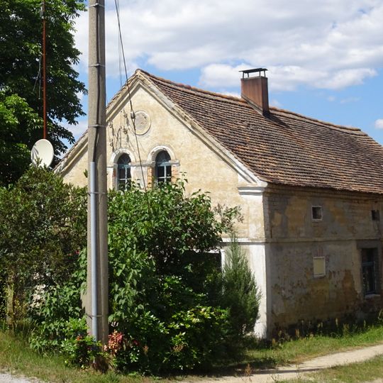 Östliches Wohnhaus mit winkligem Stallscheunenanbau, westliche Scheune und Seitengebäude eines Dreiseithofes, Scheune im hinteren Grundstücksteil sowie Toreinfahrt und Zaunsäulen, Hofbaum, Vorgarten, Streuobstwiese und Brunnen Am Eichberg 18
