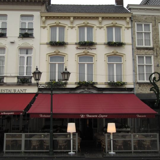 Huis met witgepleisterde lijstgevel, segmentvormig overtoogde vensters met stucversiering en nieuwe hardstenen onderpui in traditionele vormen