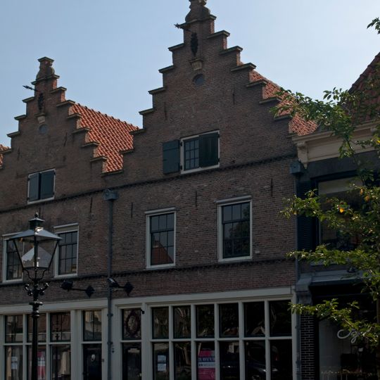 Pand met gepleisterde trapgevels met zandstenen afdekplaten en in de top uitgekraagde pinakel met gesmeed anker