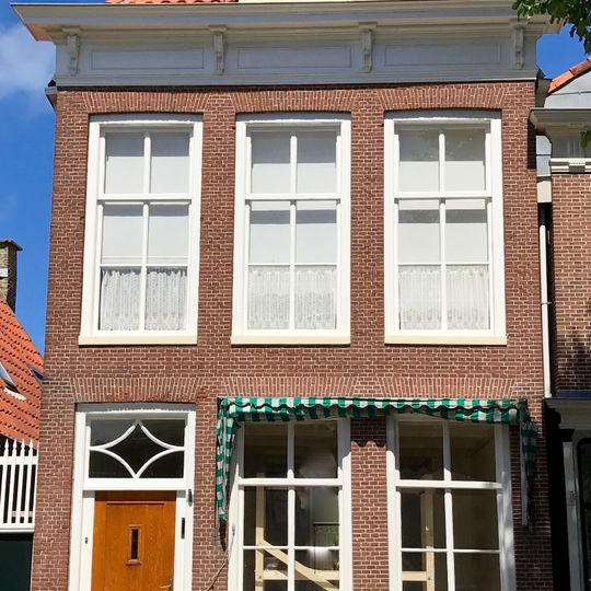 Pand kroonlijst met metopen onder schilddak met topschoorsteen en dakkapel