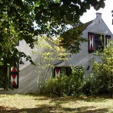 Lage landelijke gepleisterde woning met dubbele topgevel, kleine roeden, blinden