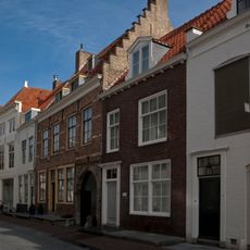 Huis met brede geverfde lijstgevel en zadeldak met zijtrapgevel