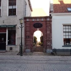 Bakstenen poortje met gebosseerde pilasters, boogomlijsting, alsmede hoofdgestel