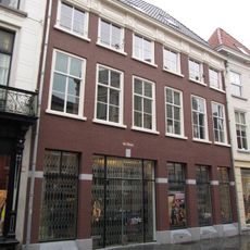 Huis met witgeverfde lijstgevel, lage bovenverdieping en houten kroonlijst met verkroppingen en ruitmotieven