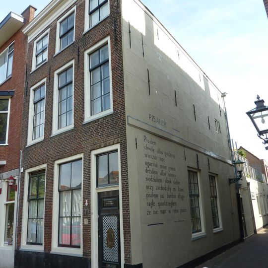 Hoekpand met twee verdiepingen onder schilddak; lijstgevel, waarin 6- en 8- en 4-ruitsschuifvensters; staafankers; gepleisterde zijgevel met blokgroeven, waarin 6-ruitsschuifvensters