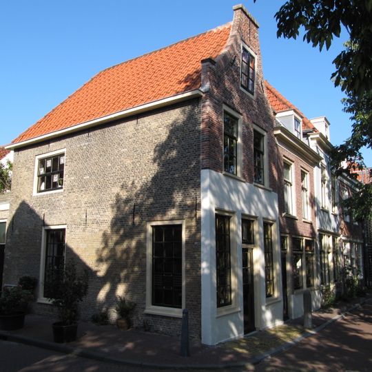 Hoekpand met verdieping, onder zadeldak, aan achterzijde een schilddak met ingezwenkte topgevel.