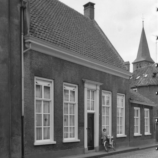 Huis met enkel begane grond en hoog zadeldak tussen puntgevels met vlechtingen en topschoorstenen