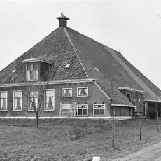 Grote stelphoeve met vier zesruitsvensters in voorgevel, melkkelder met twee kleine vensters en topschoorsteen met bord