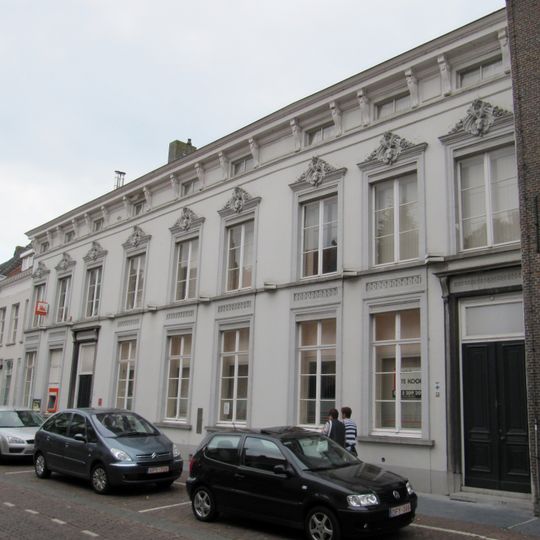 Zeer breed dwarspand, voorzien van een gepleisterde lijstgevel met hardstenen cordonlijst