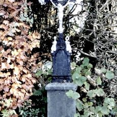 Steinsockel mit Metallkreuz und Torso.