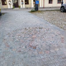 Vid den här platsen så har det funnits en skampåle. Idag så består bara platsen för pålen i mitten av en cirkeln av stenar. At this location there used to be a pillory. All that remains today is the location of the pole itself within a circle of stones.