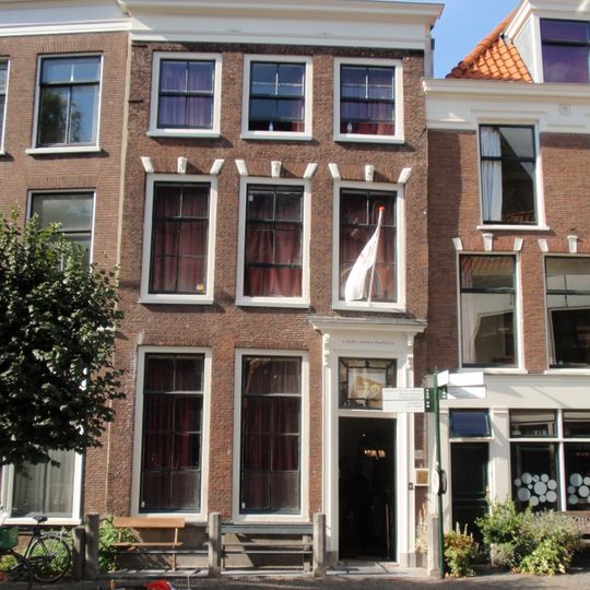 Pand met lijstgevel. Rechte strekken met maskersluitstenen boven de vensters, houten ingangsomlijsting uit begin 19e eeuw. Hardstenen stoep met palen