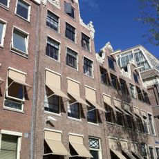 Pand met halsgevel met rijk gebeeldhouwde top van bijzonder ontwerp