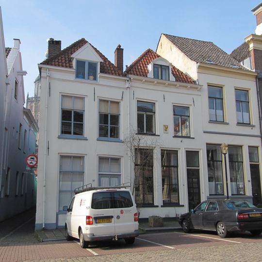 Huis onder schilddak met dakvenster, voorzien van gebogen fronton en vleugelstukken