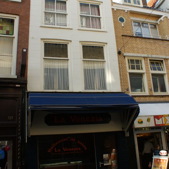 Pand met in natuursteen-imitatie gepleisterde lijstgevel en flauw getoogde vensters