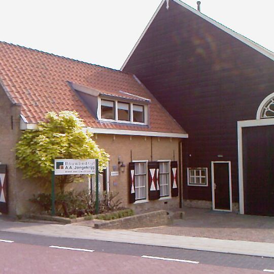 Boerderij, waarvan het woonhuis een puntgevel met vlechtingen heeft. Vensters met zesruitsschuiframen en luiken.