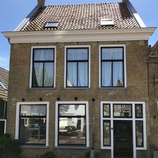 Pand met verdieping onder dwars zadeldak tussen topgevels met oudere hoekschoorsteen