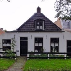 Pand met zesruitsvensters en houten goot op blokjes onder aan de voorzijde afgewolfd zadeldak